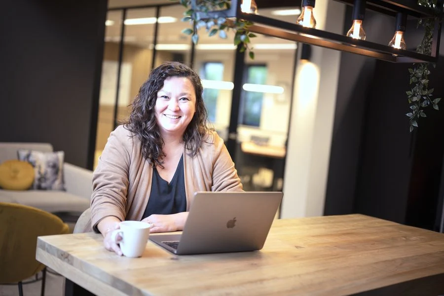 Collega werkt lachend op haar laptop