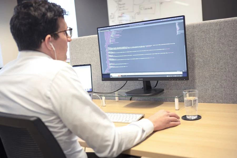 Ontwikkelaar werkt aan code op een groot scherm