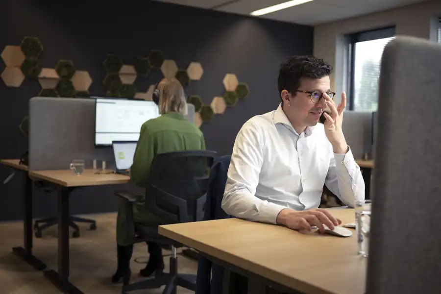 Collega aan zijn werkplek in de kantoortuin