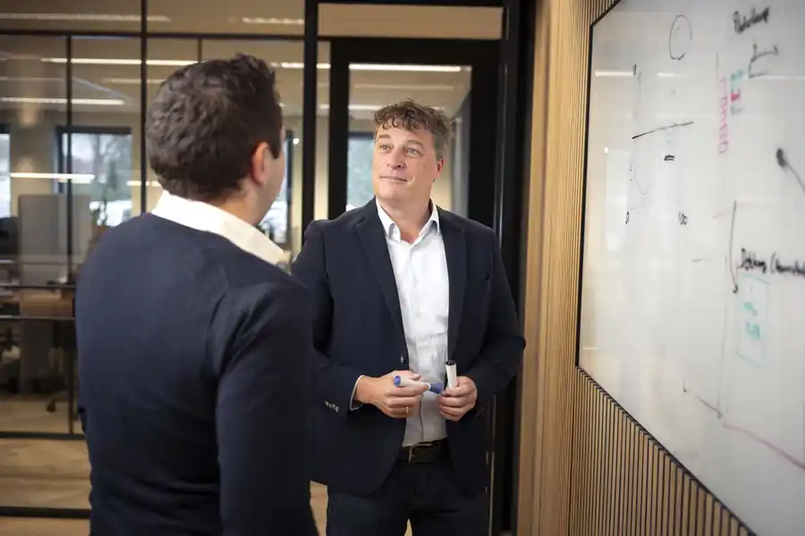 Twee collega's in overleg bij het whiteboard